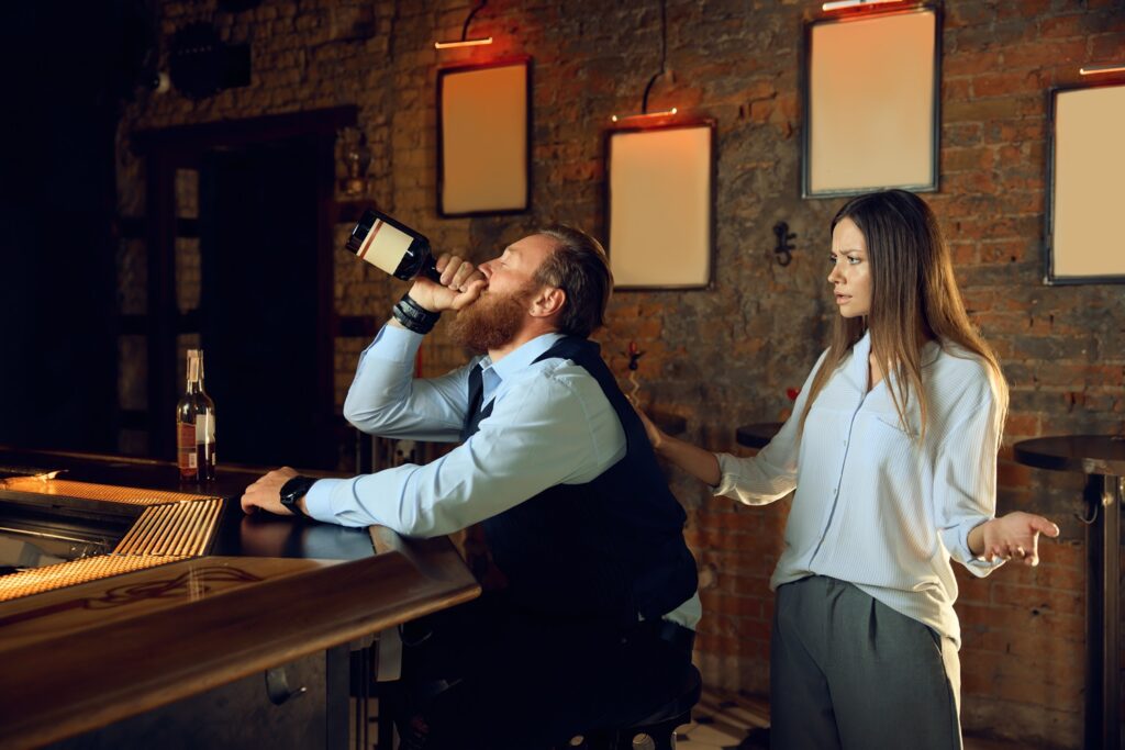 Woman confronting a man drinking at a bar during a tense moment